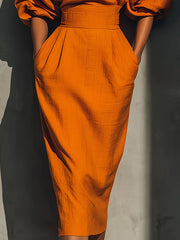 Close view of orange puff sleeve midi dress skirt with pleats and waistband
