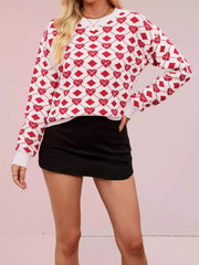 Front view of a white knit sweater with red heart and diamond argyle pattern, hand on hip