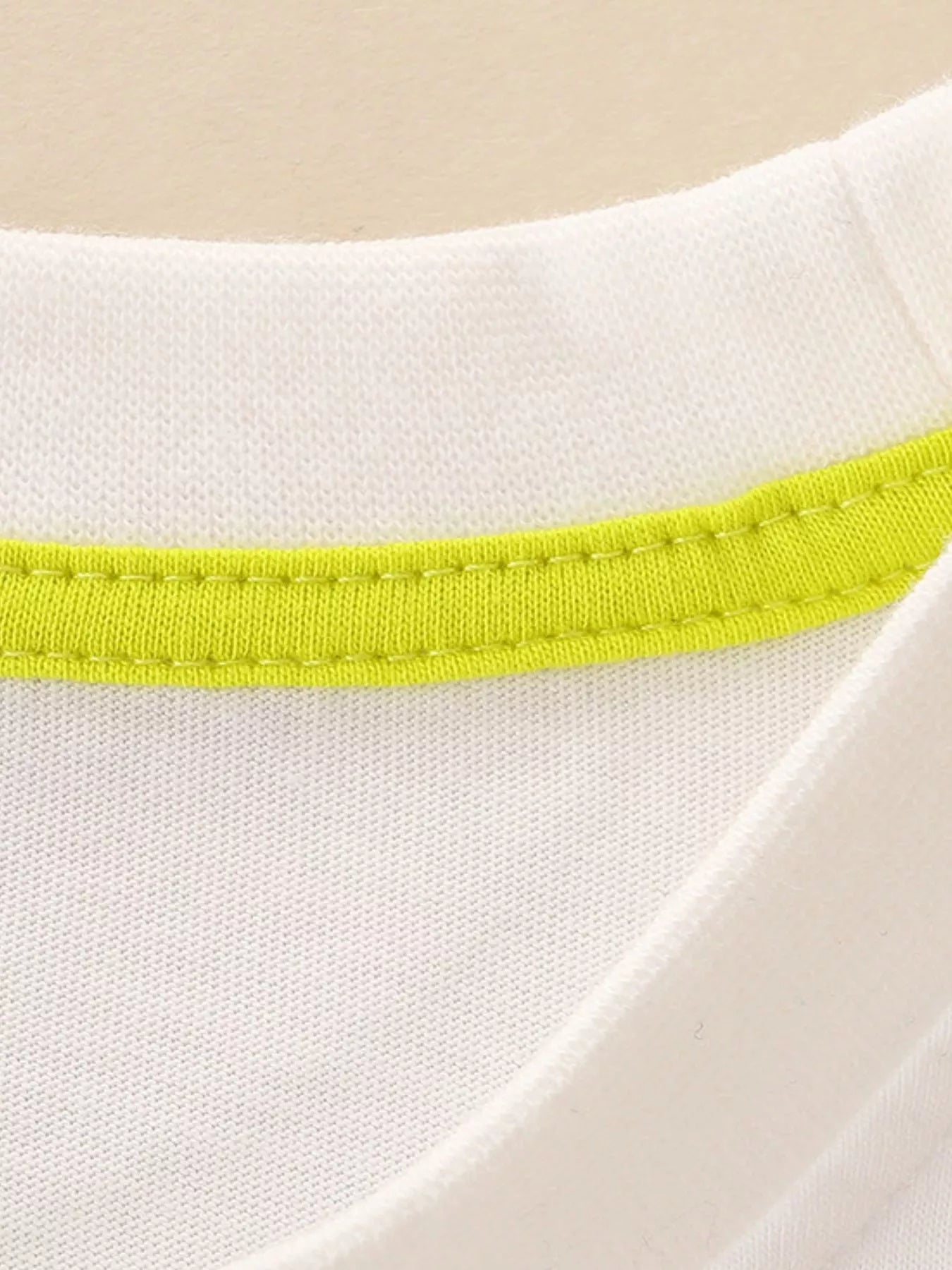 Close-up of cream children's t-shirt neckline with bright lime green inner trim