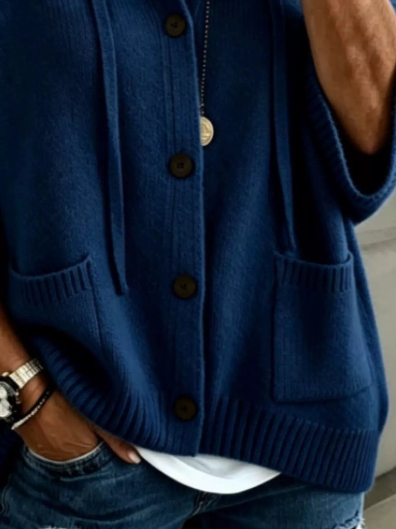 Detail view of the navy cardigan showing brown buttons, patch pockets and ribbed hem