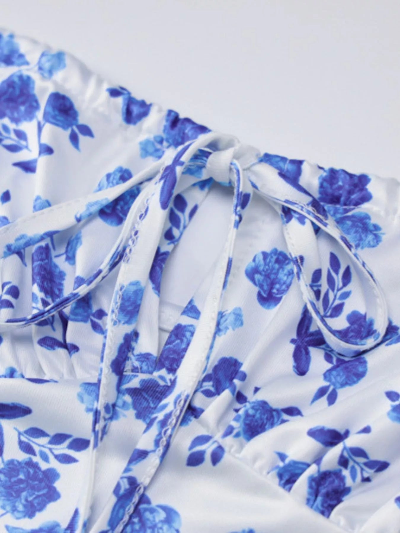 Close up of blue floral print fabric showing front tie and ruched bodice of bodycon maxi dress