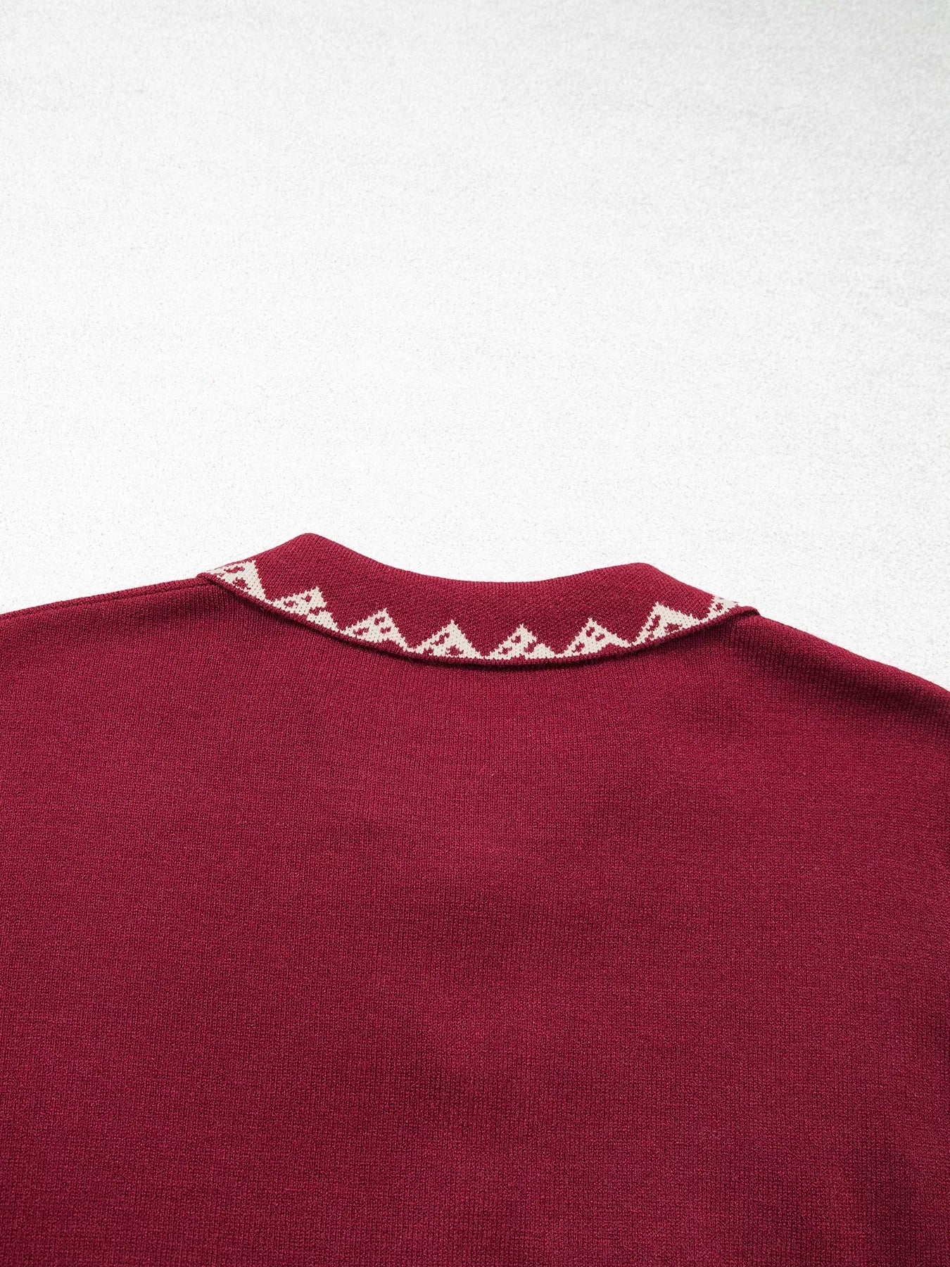 Close back view of the burgundy cardigan collar with cream zigzag trim