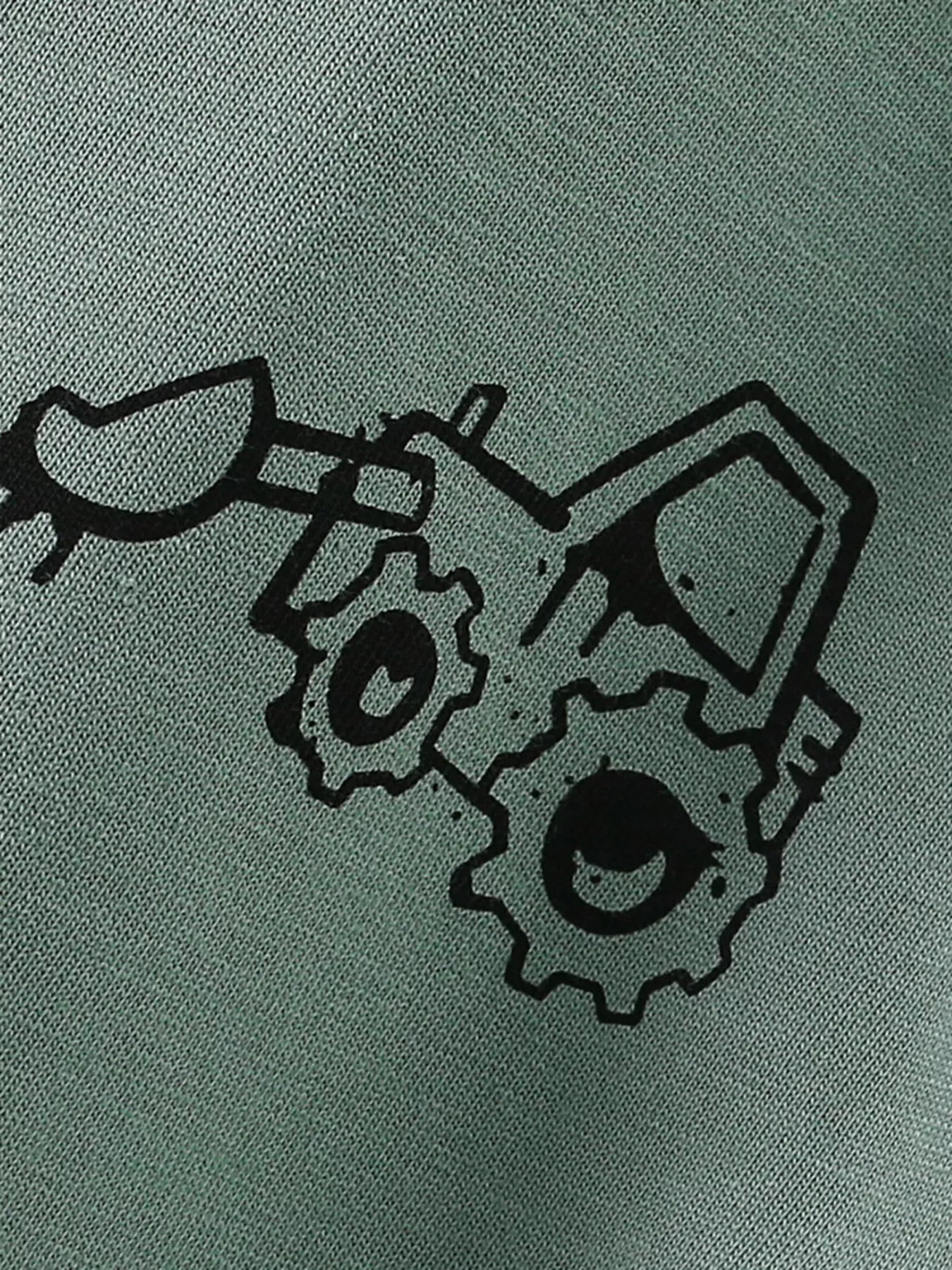 Close-up detail of the black cartoon excavator graphic printed on sage fabric
