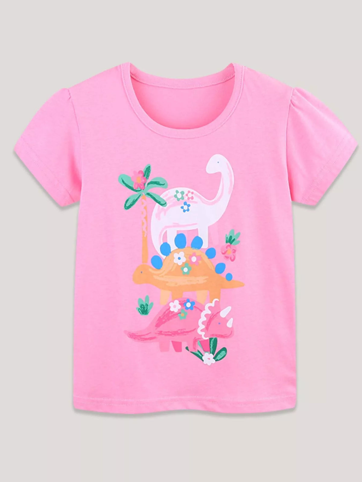 Pink children's short sleeve t-shirt laid flat with stacked dinosaurs flowers and palm tree