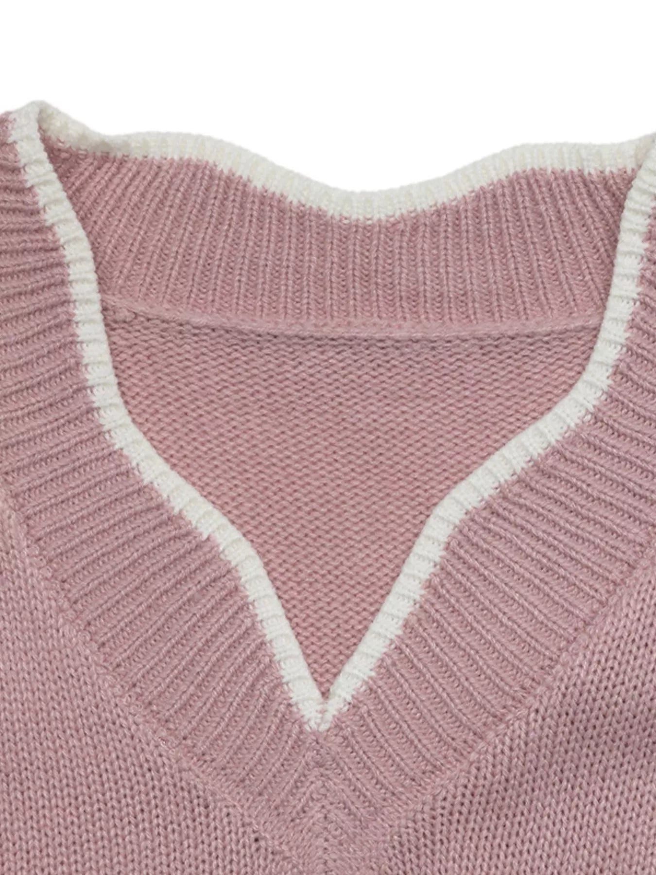 Close up of the pink sweater V neck with white trim and ribbed knit detail.