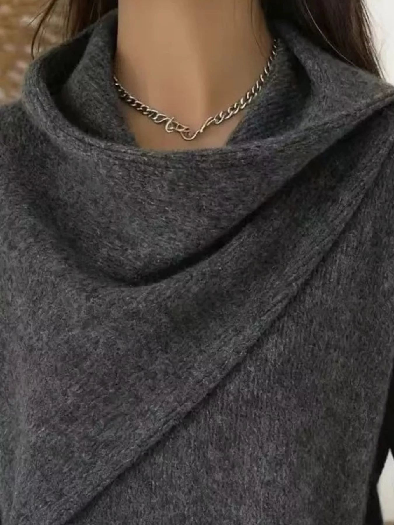 Close-up of the dark gray cowl neckline showing the draped asymmetric collar and fine knit texture