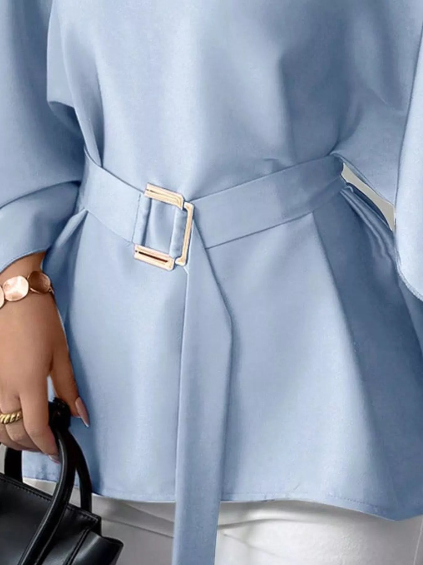 Close detail of light blue batwing sleeve blouse gold buckle belt and flared hem