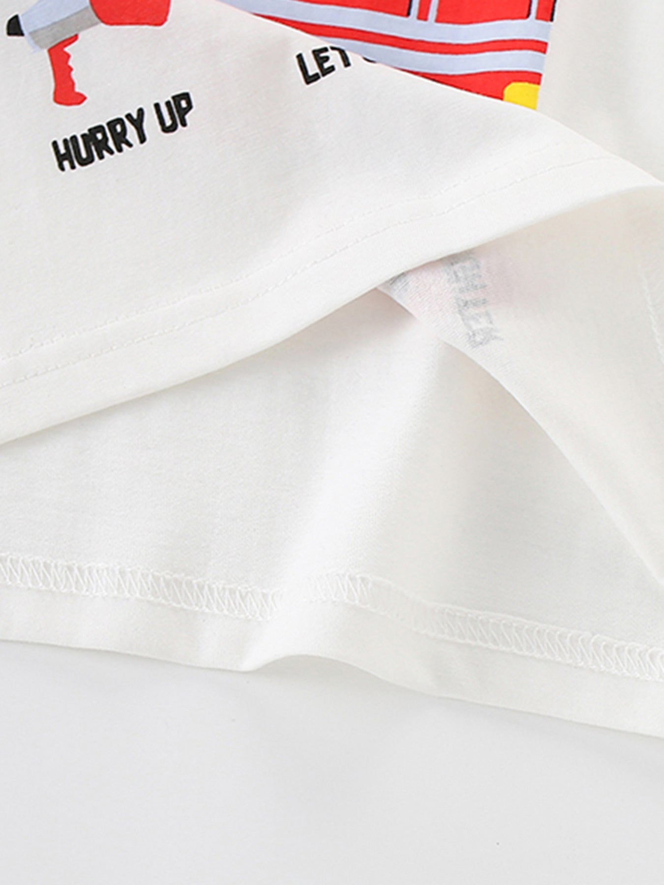 Close-up of white children's t-shirt hem stitching with partial lower graphic visible