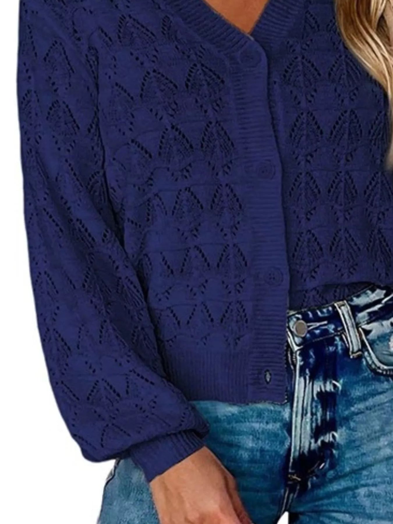 Side close view of navy openwork knit cardigan showing button front and hem.