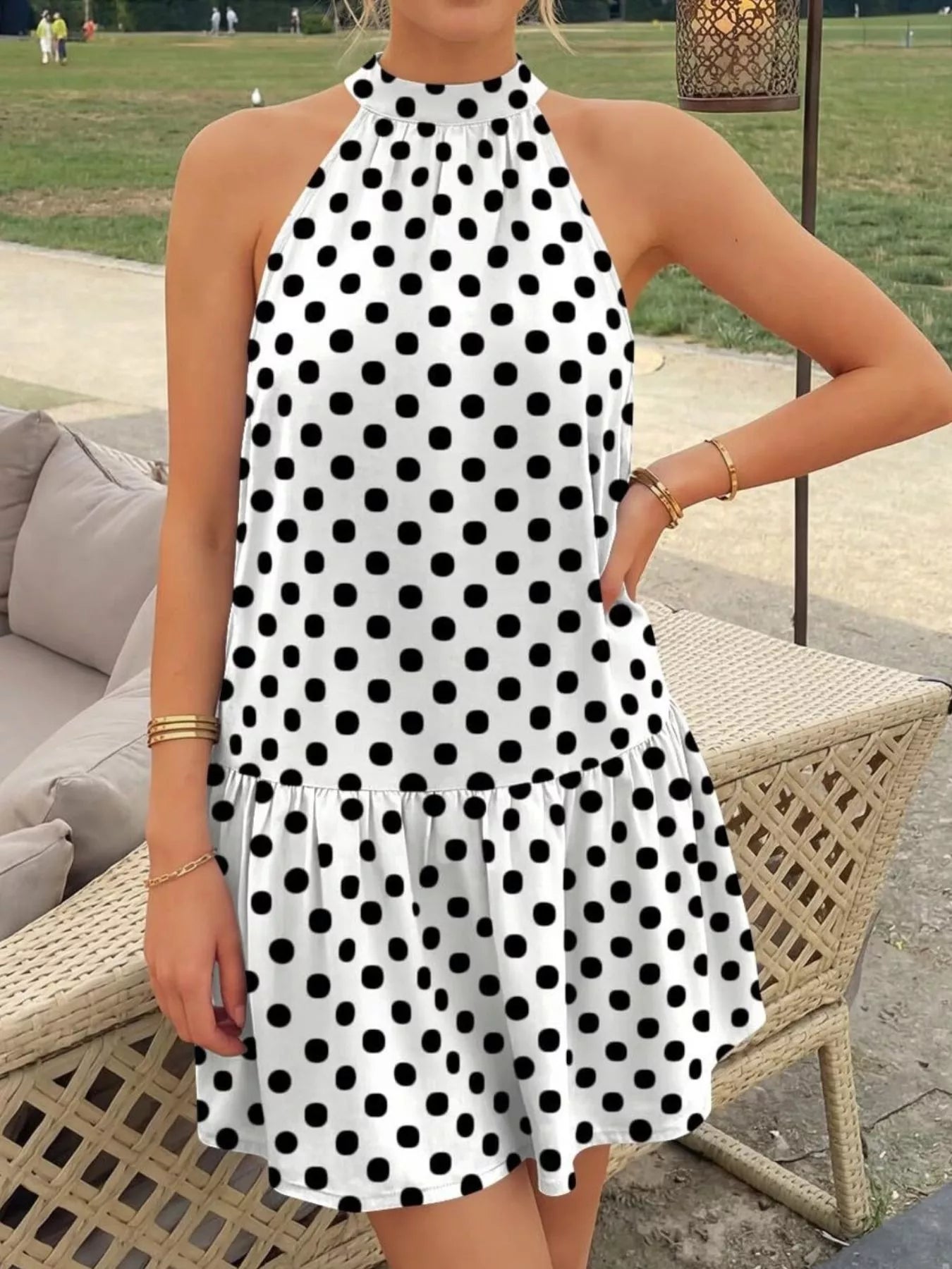 White polka dot halter neck mini dress worn standing outdoors with a ruffled hem