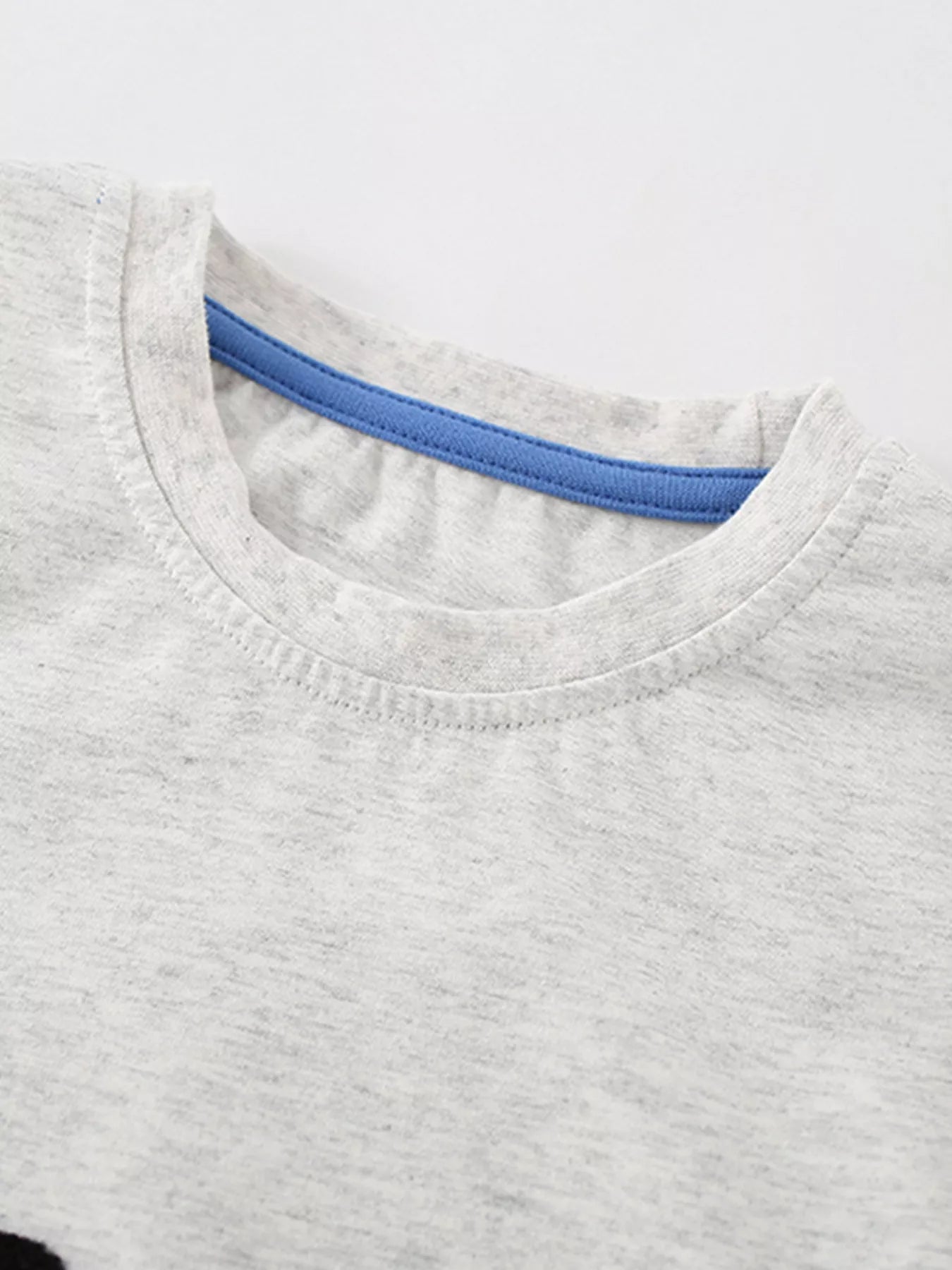 Close view of the round neckline with blue inner trim on the light gray children's T-shirt