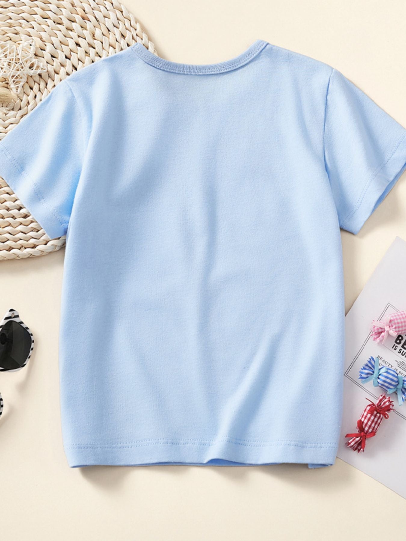 Back view of a plain pastel blue children's short sleeve tee laid flat