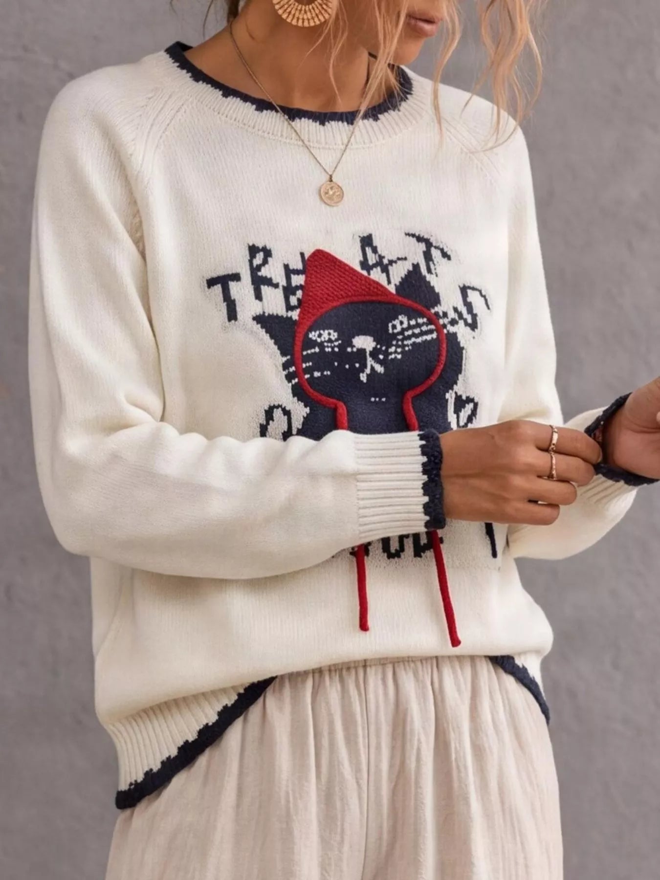 Side view of beige cat sweater with black cat and red strings
