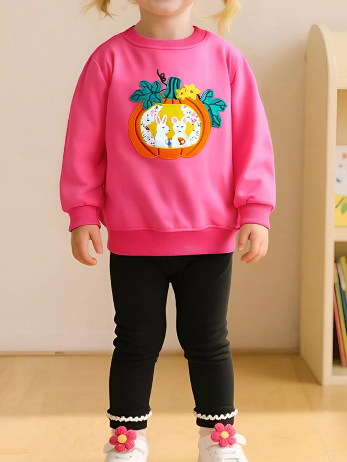 Front view of a strawberry pink children's sweatshirt with an orange pumpkin rabbit applique