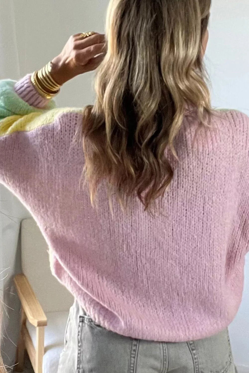 Close back view of the pink knit cardigan with yellow and mint shoulder panels