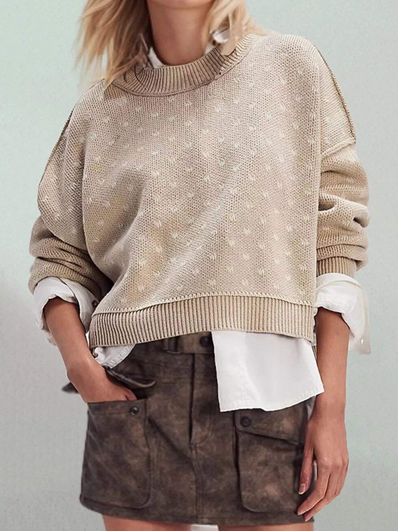 Front view of the khaki dotted sweater with ribbed hem and dropped shoulder seams on model