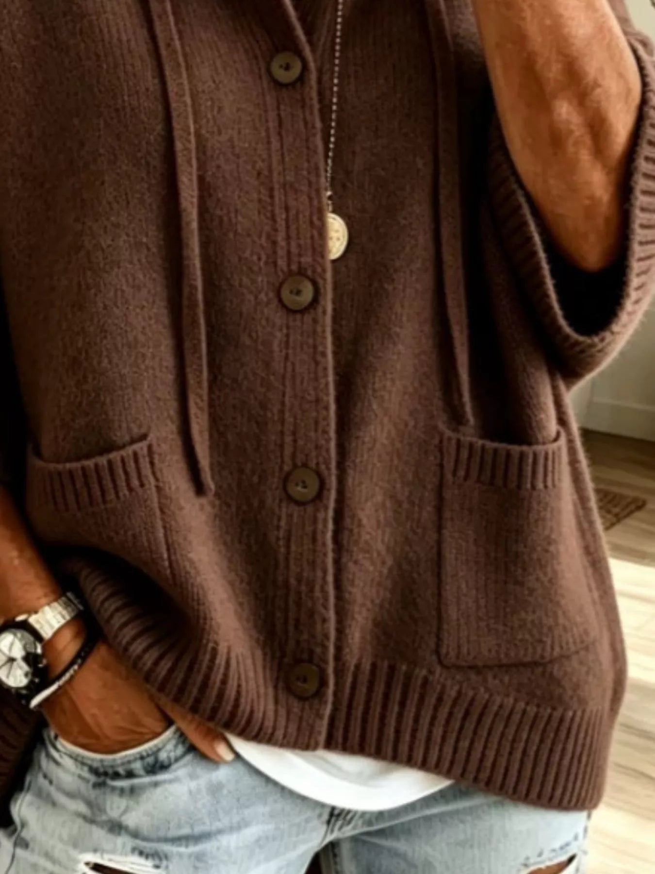 Detail view of the dark brown cardigan showing brown buttons, patch pockets and ribbed hem