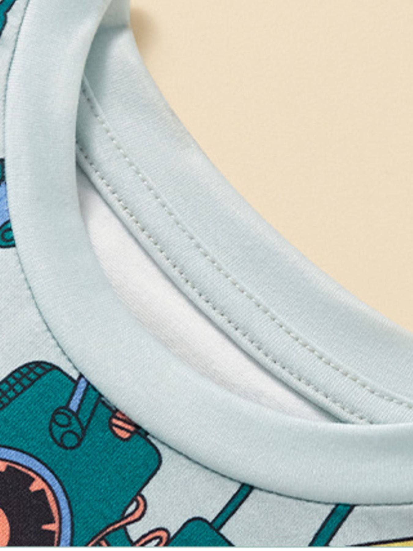 Close-up of the stitched crew neckline on the light children's construction vehicle tee