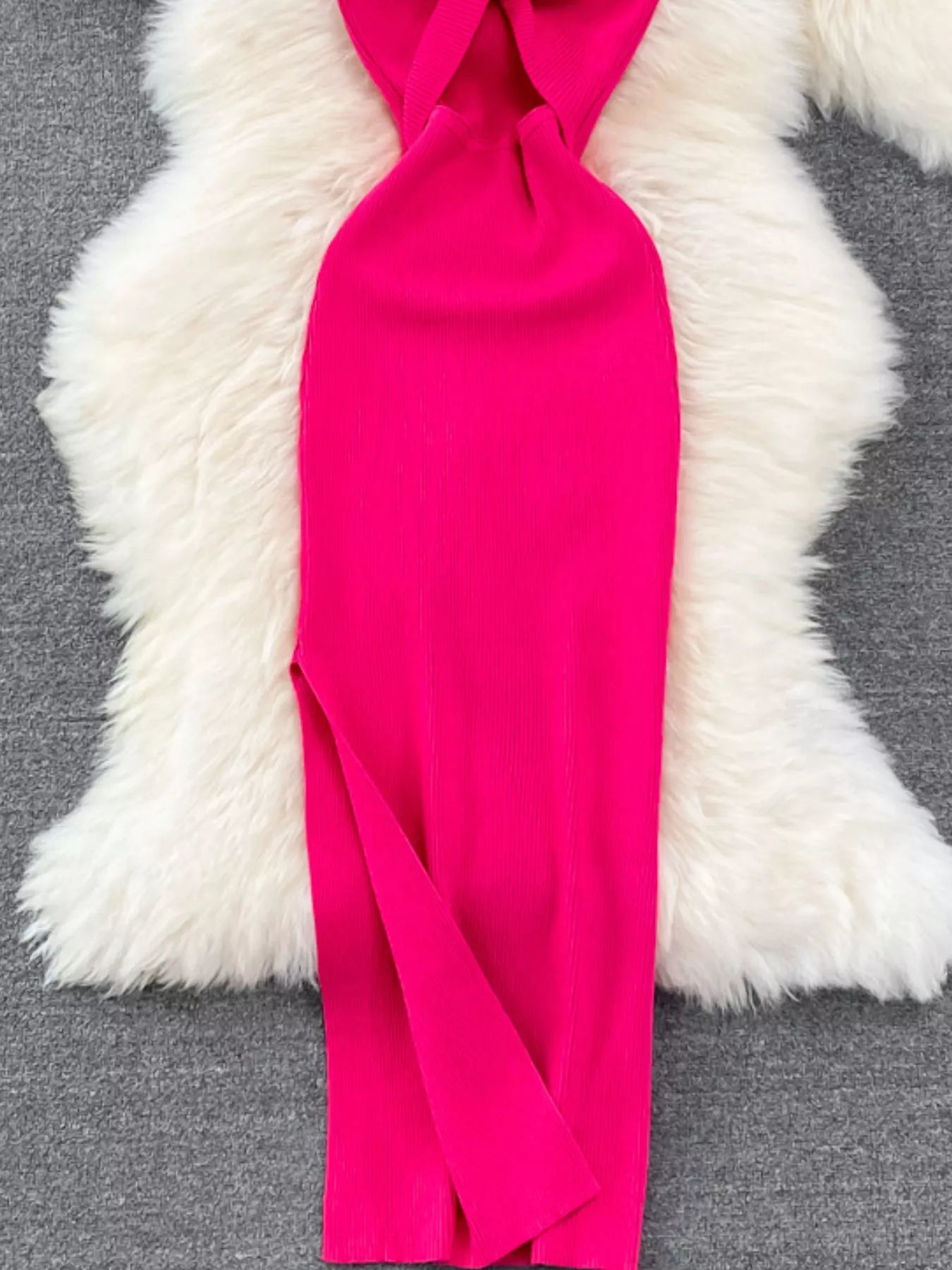 Lower skirt of rose red ribbed knit midi dress showing side slit detail