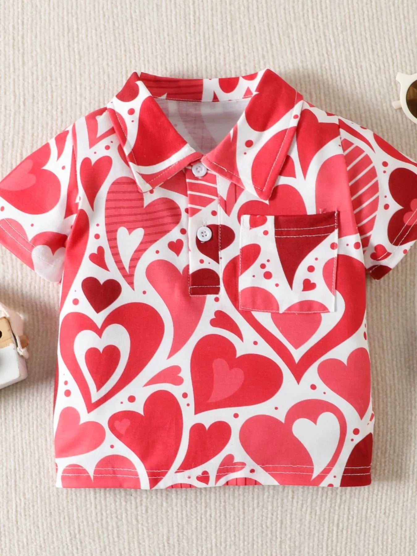 Flat front view of a red and white children's polo with large heart print collar and pocket