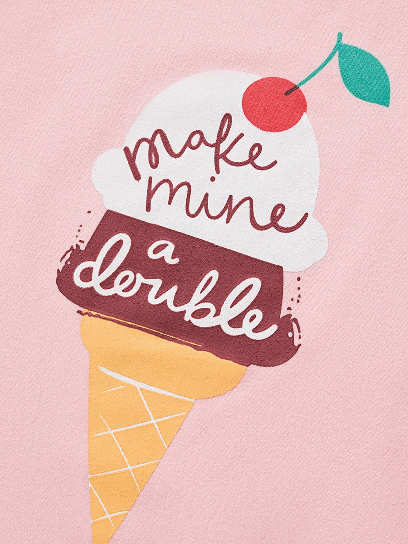 Close-up detail of the ice cream cone graphic with a cherry and script lettering on pink fabric