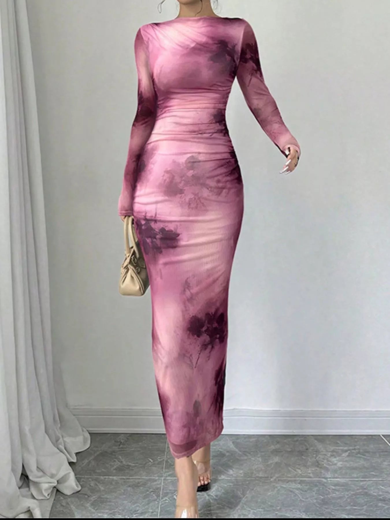 Pink tie dye long sleeve bodycon maxi dress worn front facing while holding a small handbag