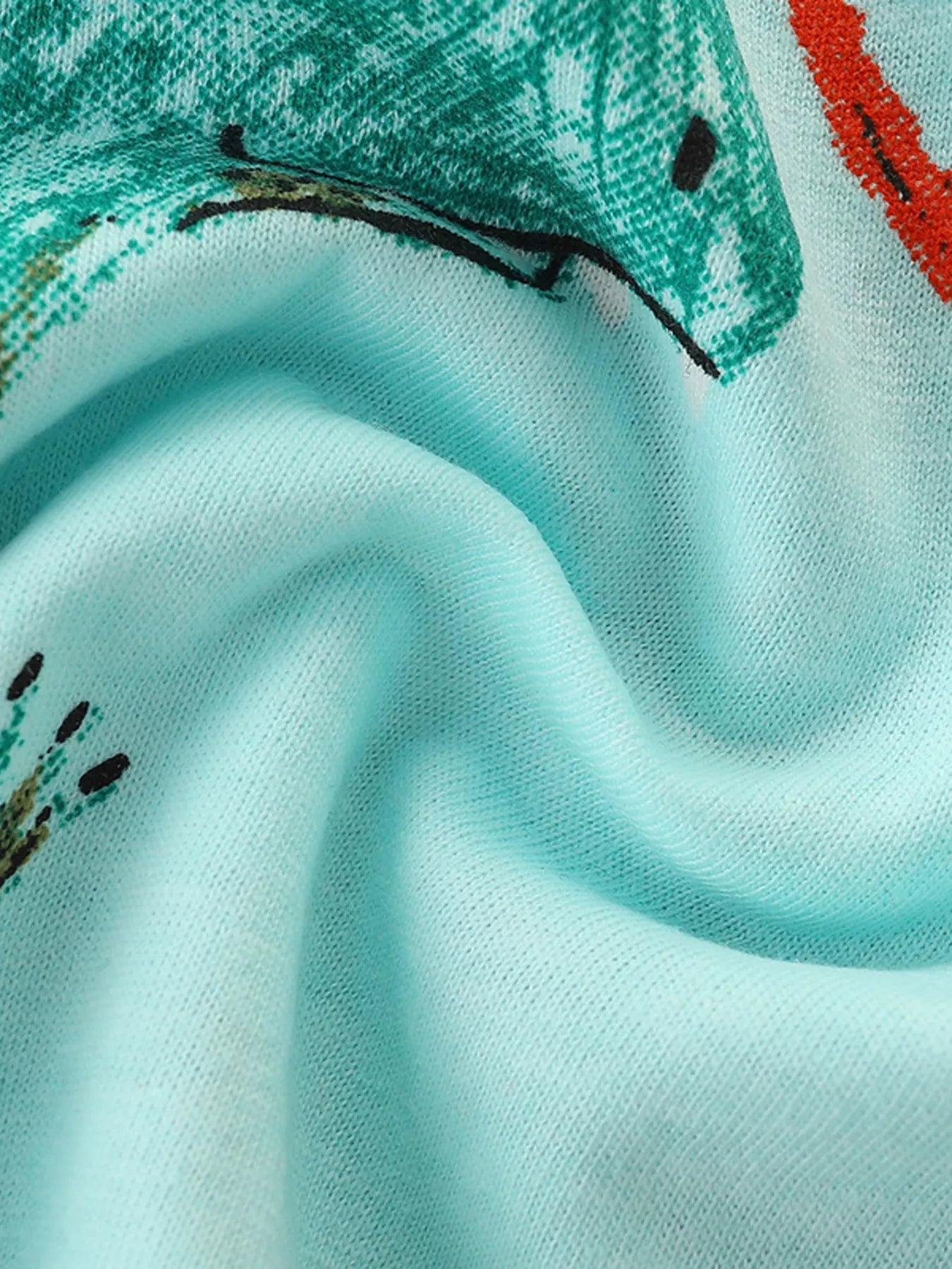 Close-up detail of the soft aqua fabric showing part of a teal dinosaur print