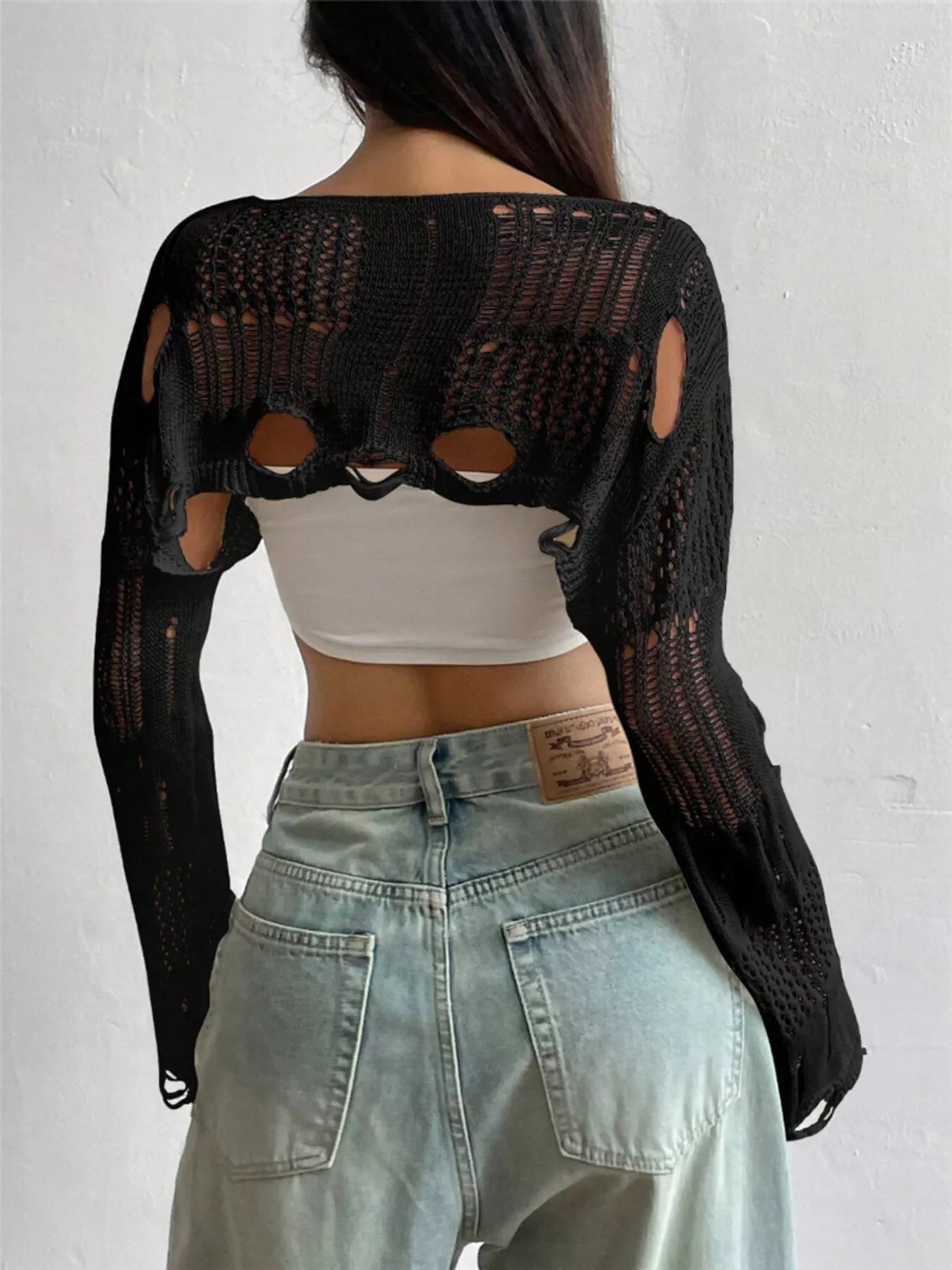 Back view of black distressed cropped knit cover up with openwork and cutouts.