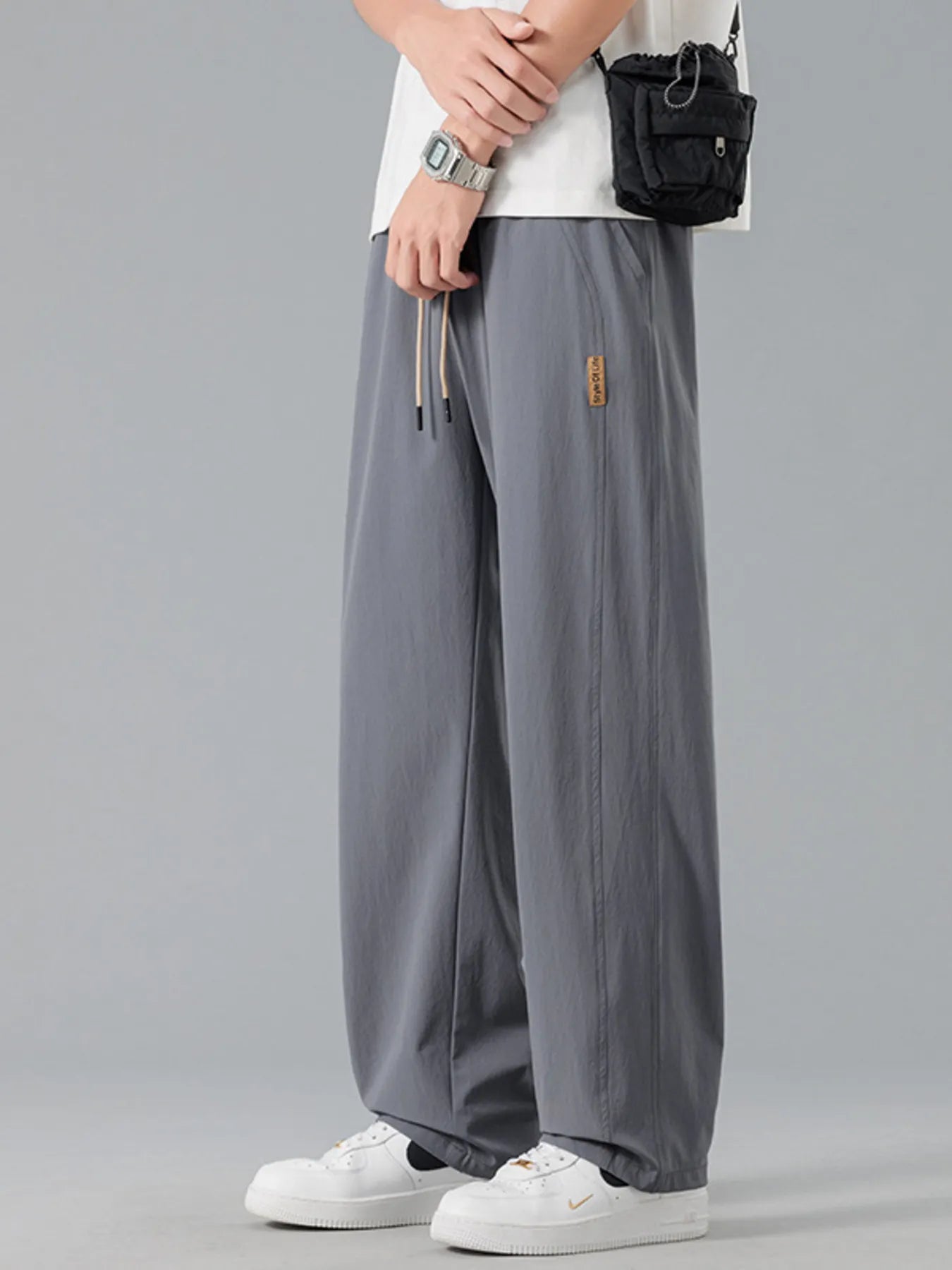 Men's grey loose-fit casual pants with a drawstring waist and pockets.