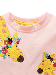 Close view of the neckline and floral giraffe applique on a blush pink children's t shirt