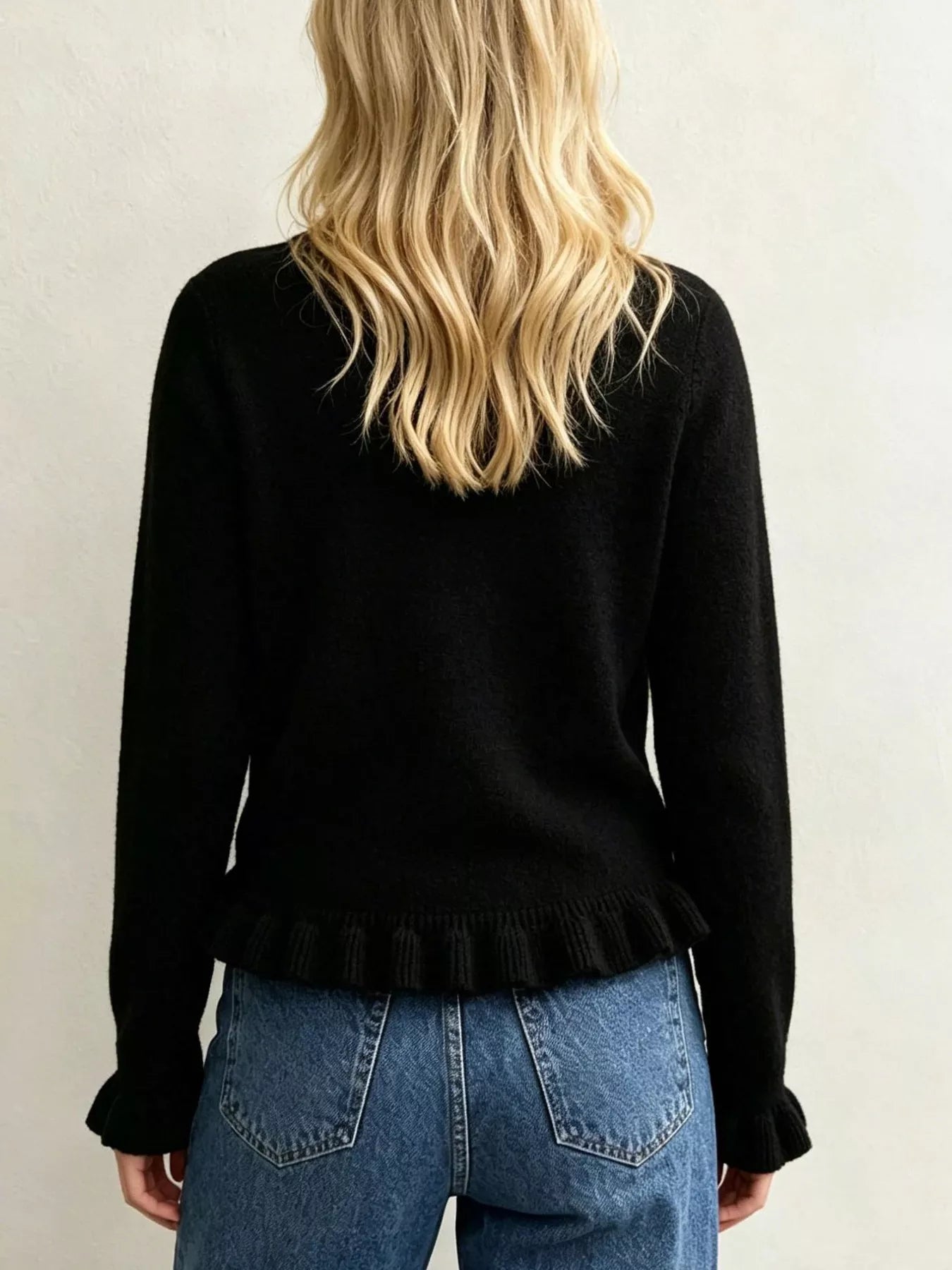 Back view on-model of black crew neck sweater with ruffled hem and cuffs