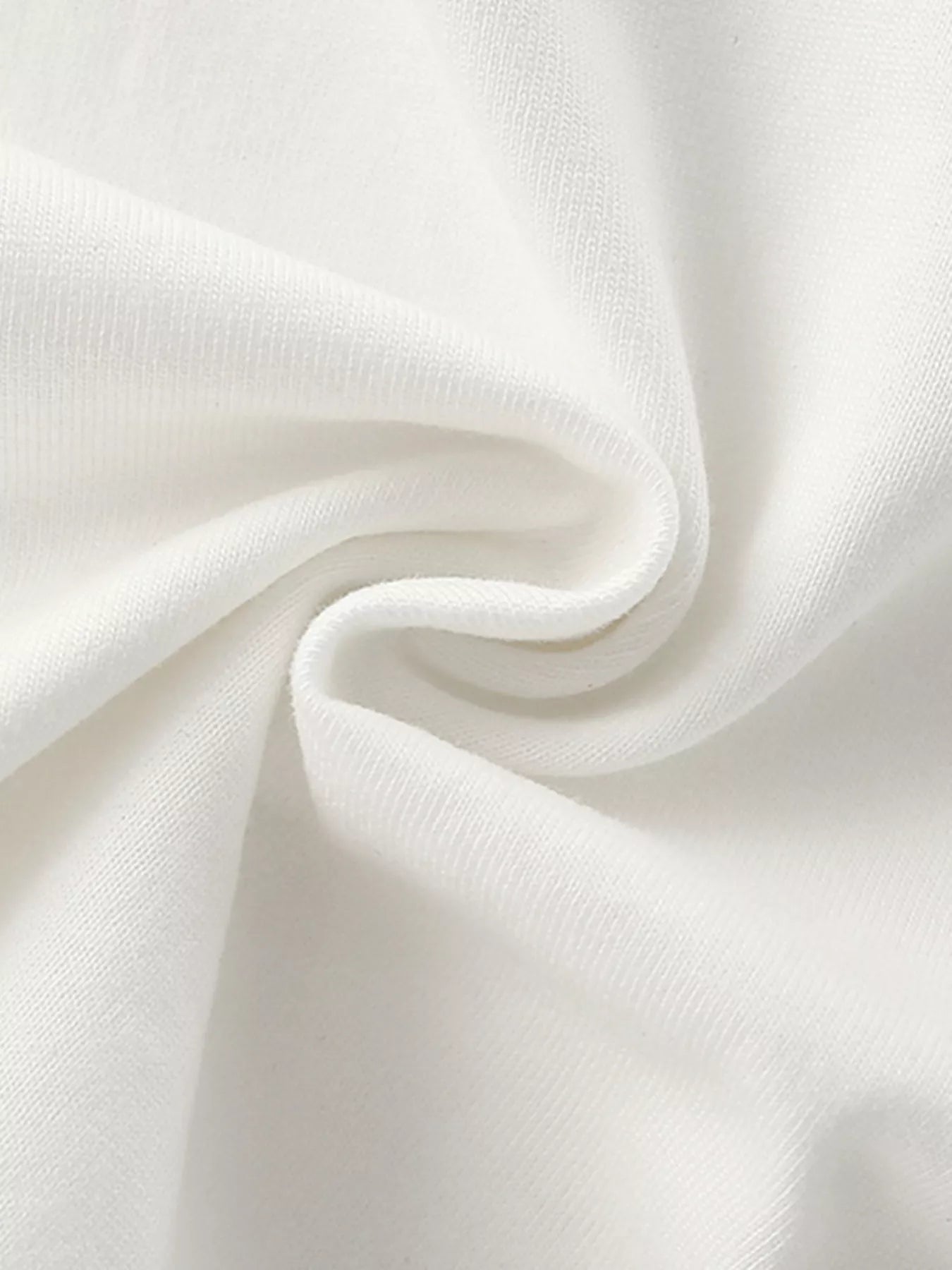 Close-up of soft white fabric texture of children's t-shirt, gathered in folds