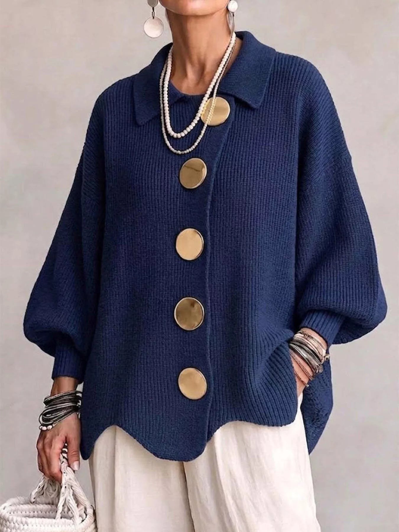 Front view of a navy knit cardigan with large gold buttons and lantern sleeves
