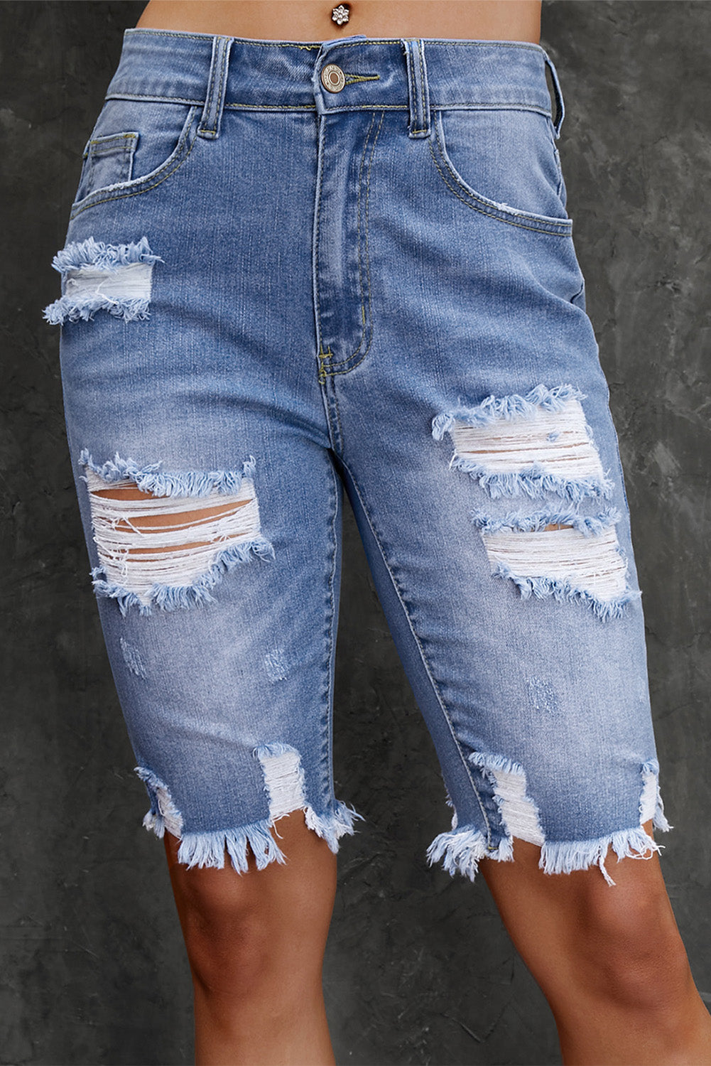 Women's acid-wash denim Bermuda shorts with distressed detailing and frayed hems.