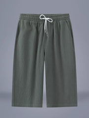 Men's army green cropped casual pants with a drawstring waist and pockets.