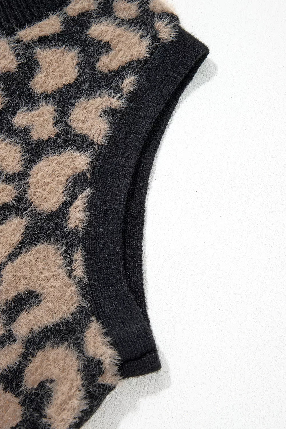 Close up of black ribbed armhole trim on leopard print knit vest.