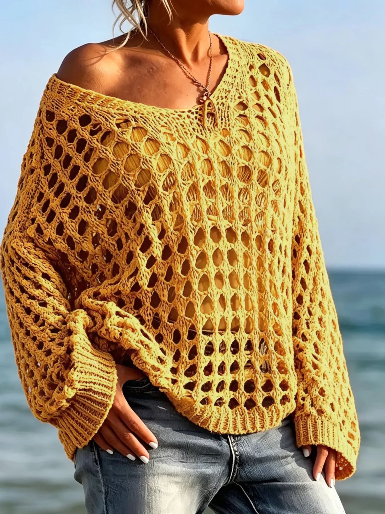 Front view of yellow openwork crochet knit cover up worn off the shoulder at the beach.