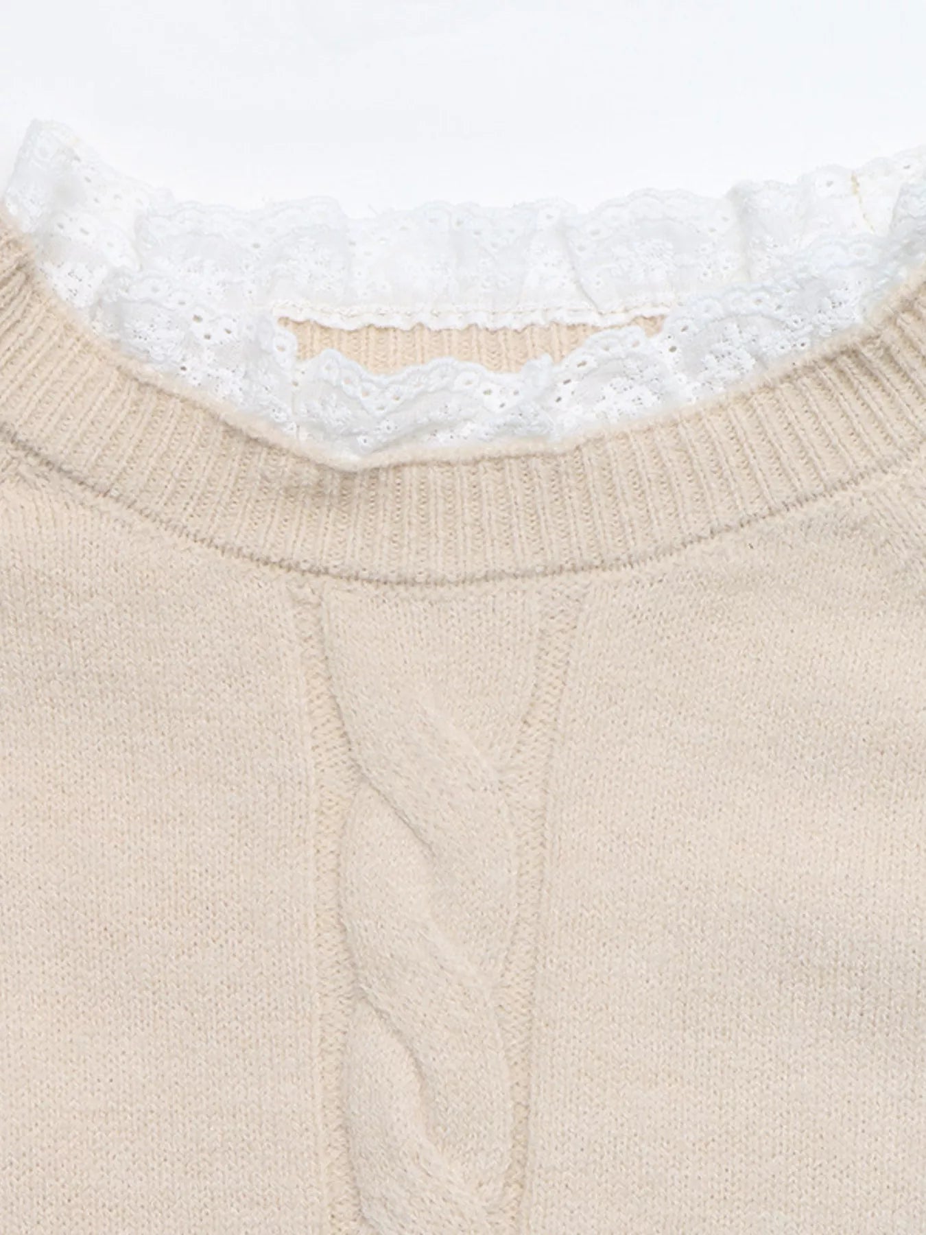 Close up of beige cable knit sweater dress neckline with white lace trim and ribbed collar