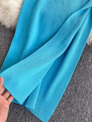 Close detail of bright blue ribbed knit fabric and side slit hem held in hand