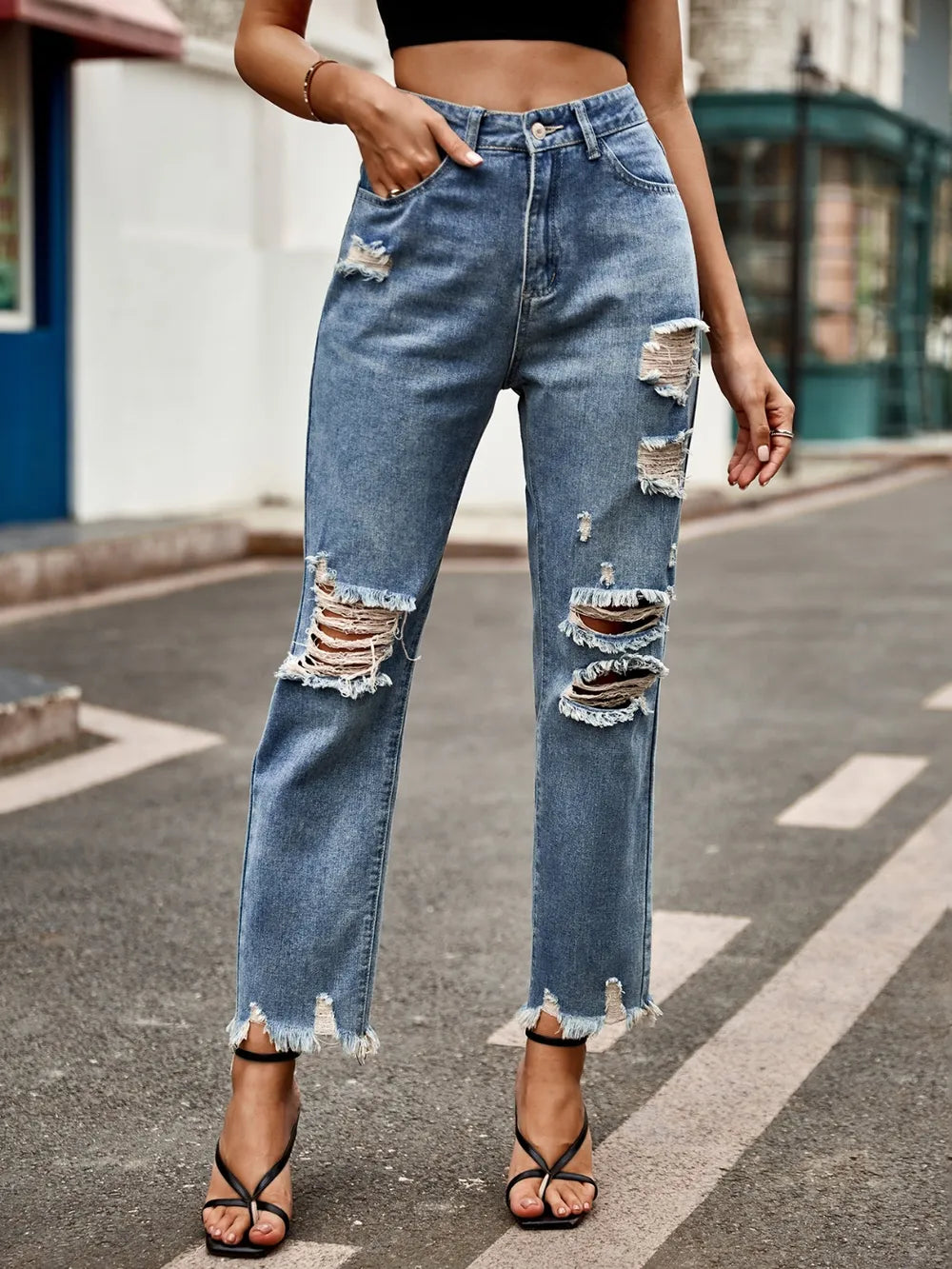 Women's distressed jeans with a raw hem, button fastening, and pockets.