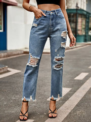 Women's distressed jeans with a raw hem, button fastening, and pockets.