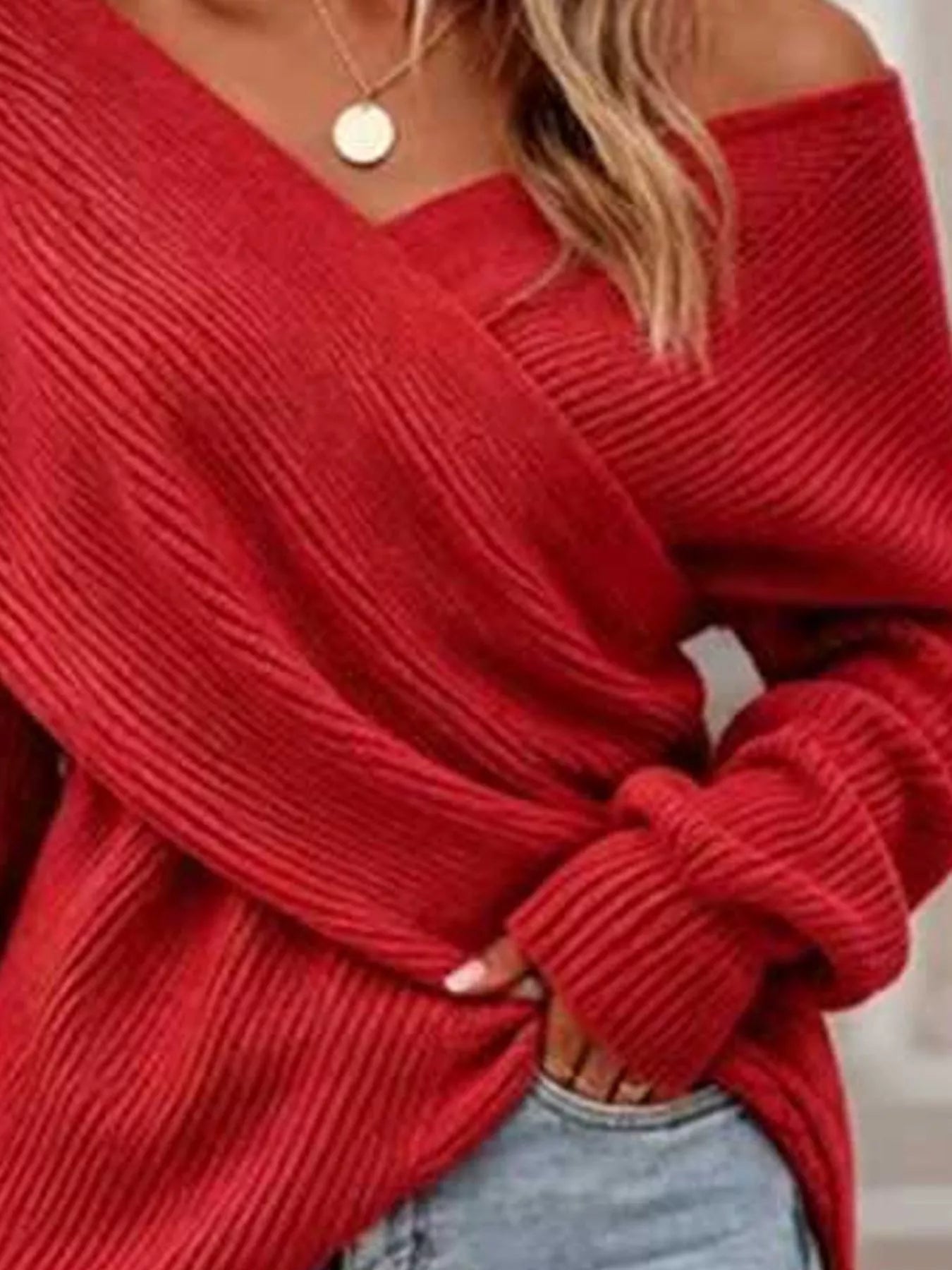 Close front view of red ribbed knit sweater showing crisscross V neckline detail.