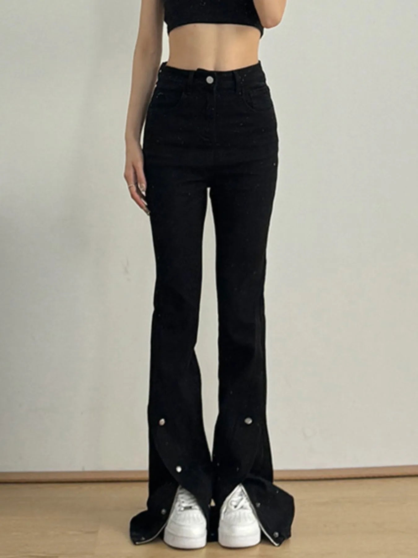 Women's black high-waisted flare jeans with slit detailing and a button-and-zip closure.