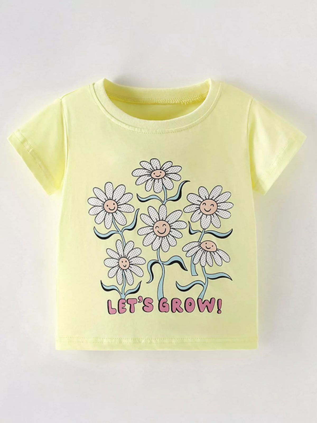 Flat front view of a light yellow children's tee with smiling daisies and pink lettering below