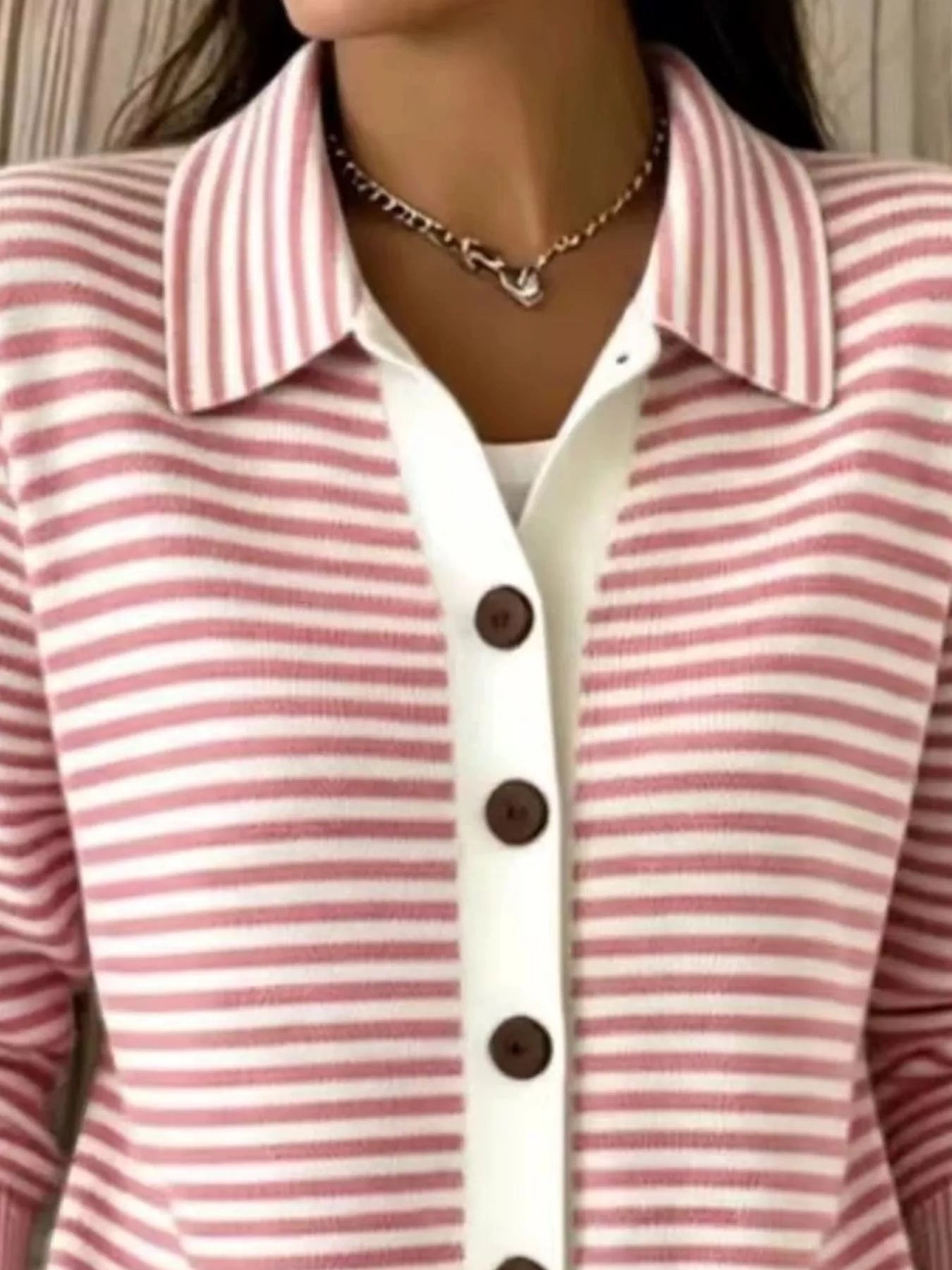Close-up of the collar and brown buttons on a pink and white striped knit cardigan