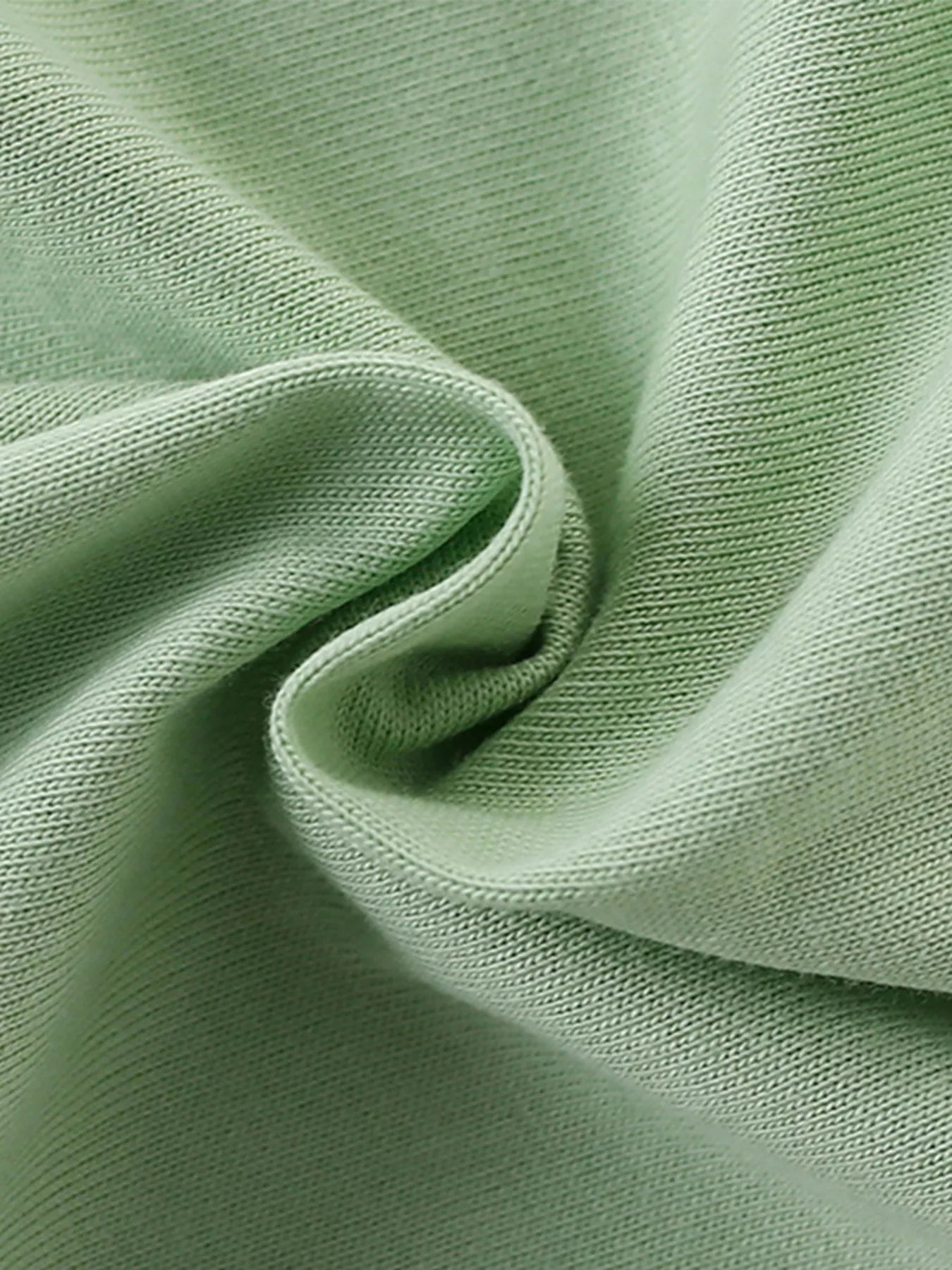 Close view of the soft twisted sage green knit fabric texture of the children's T-shirt
