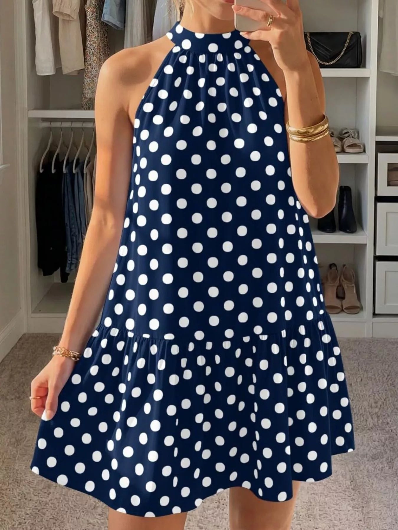 Navy blue polka dot halter neck mini dress shown front in a mirror selfie indoors