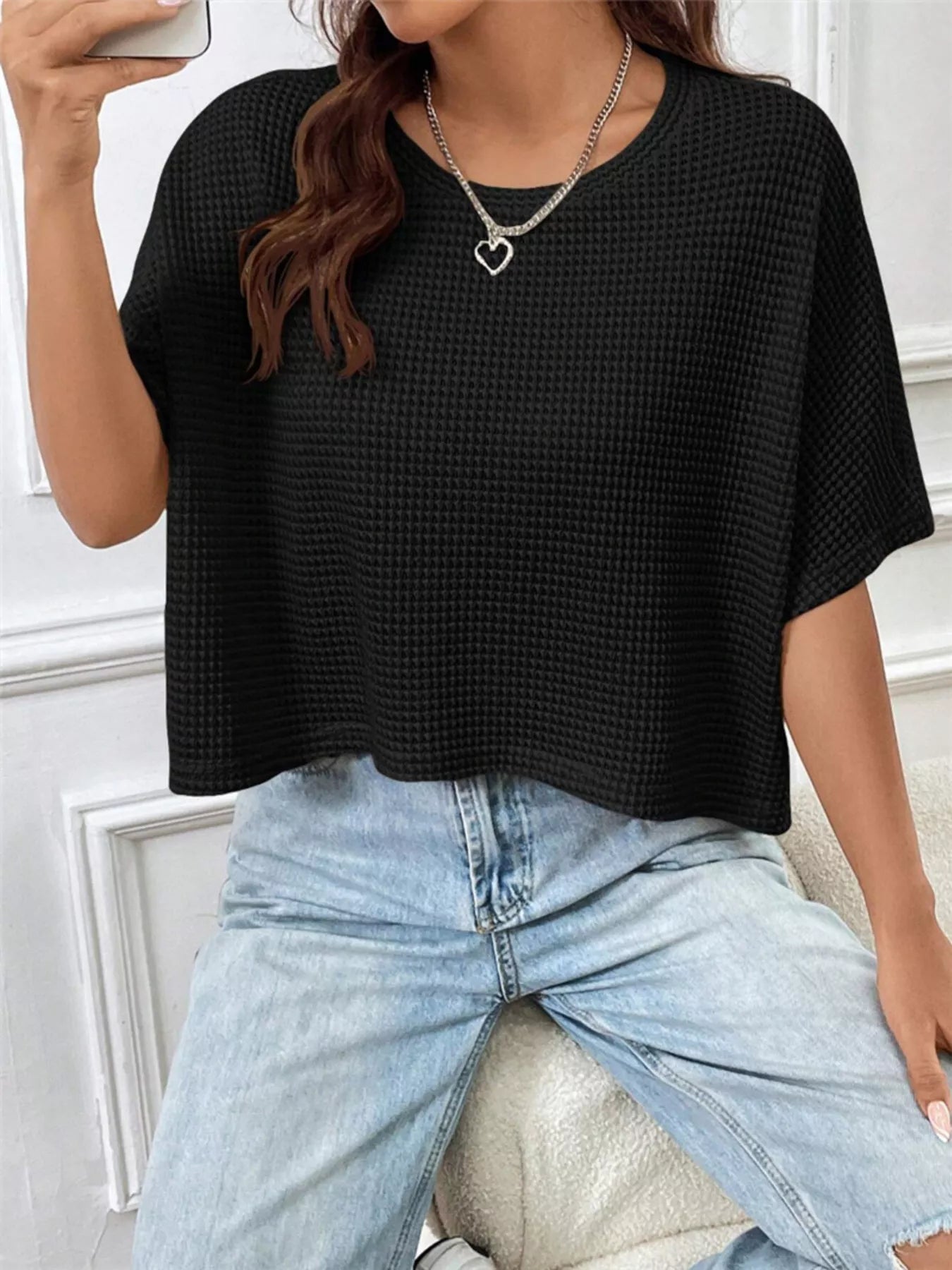 Black waffle-knit cropped T-shirt with short sleeves, shown styled with light-wash jeans.