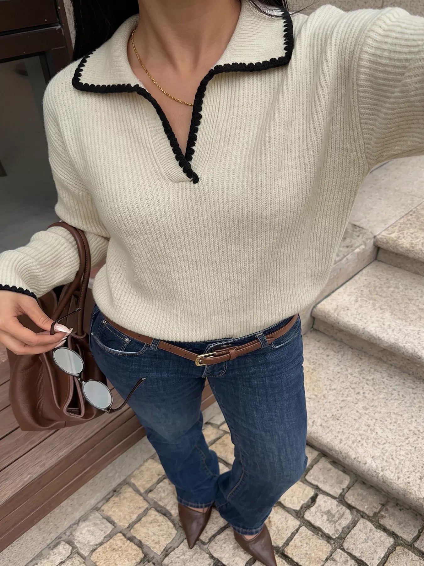 Front view of a cream dropped shoulder sweater with black scalloped trim and ribbed knit