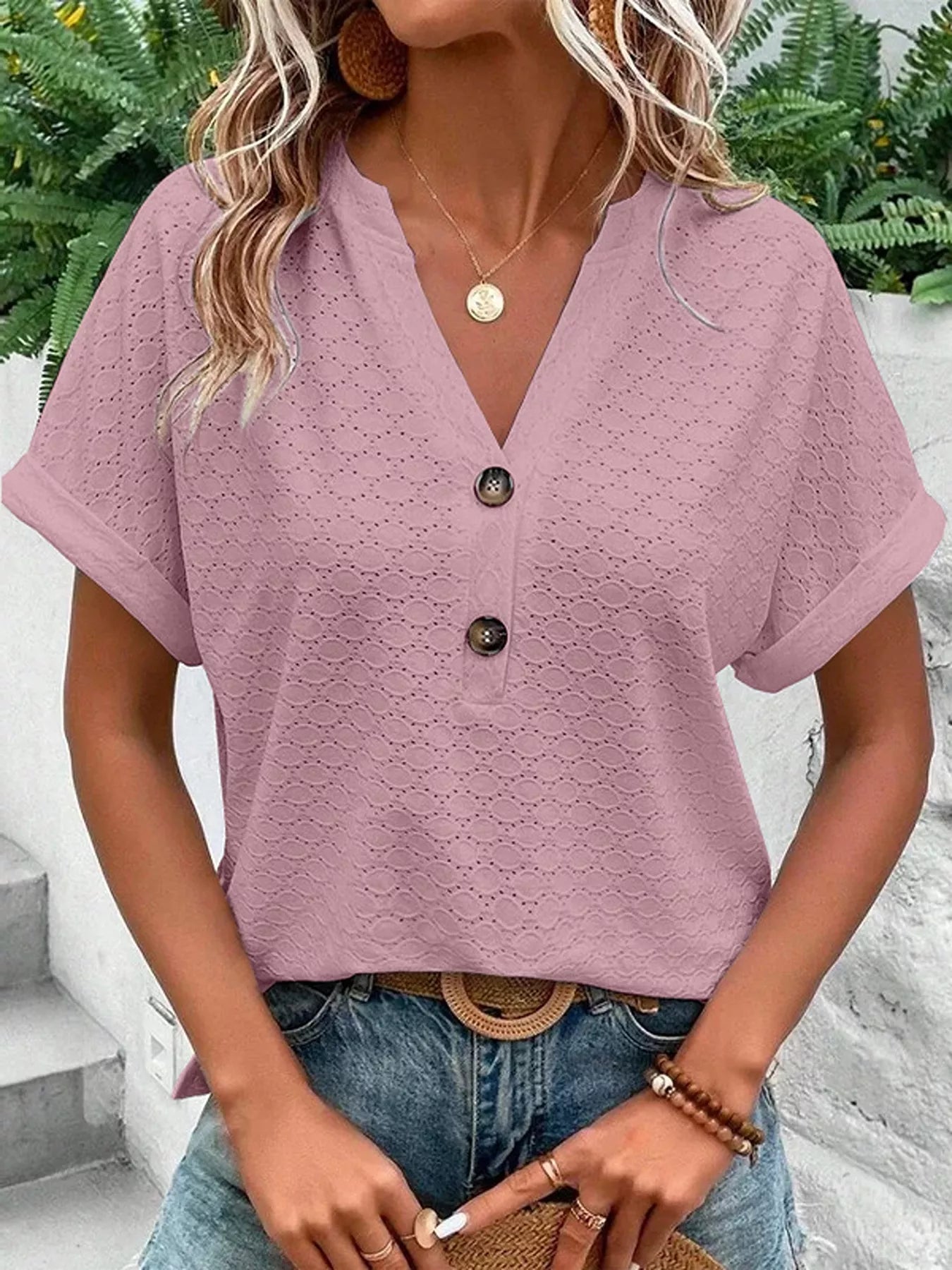 Mauve short-sleeve top with notched neckline, textured eyelet pattern, and button-front detail.